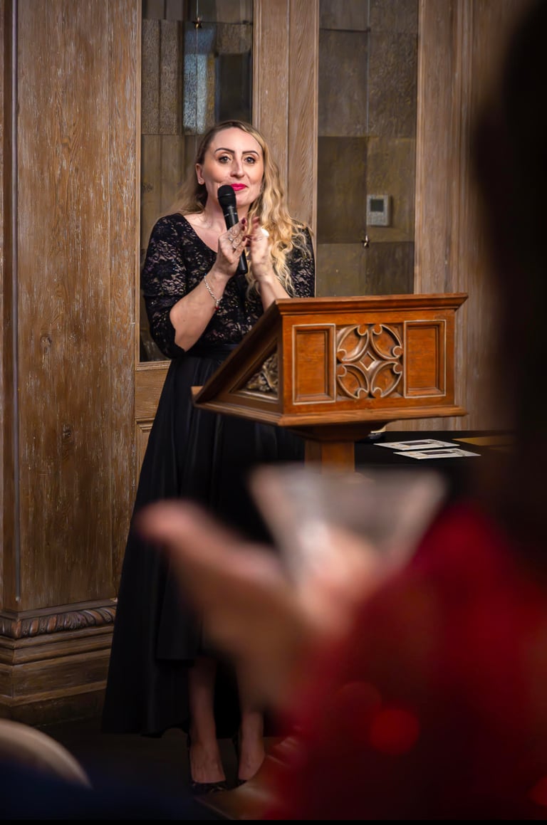 a woman in a black dress standing at a podium with a microphone