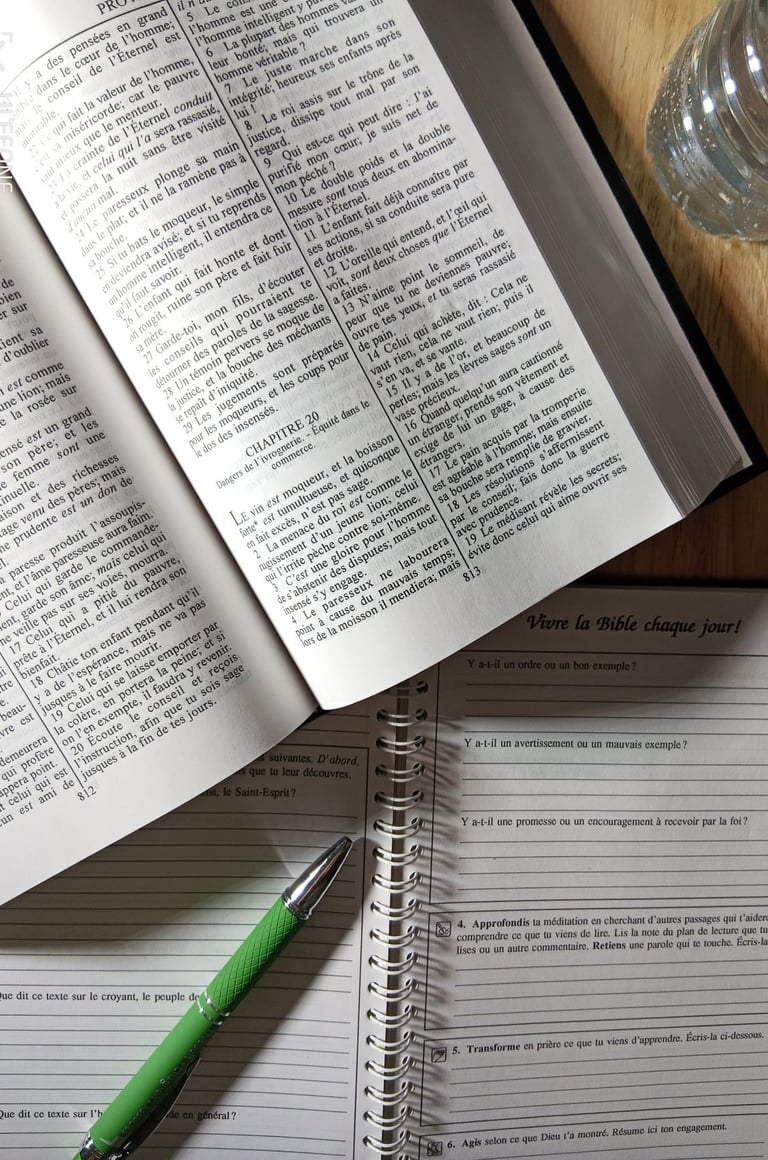 Bible Ostervald ouverte sur le proverbes 20, cahier, stylo et bouteille d'eau sur la table 