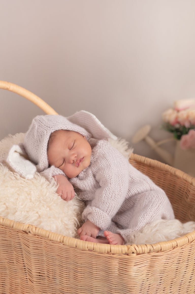 un bebé recién nacido en una cobija dentro de una canasta de paja