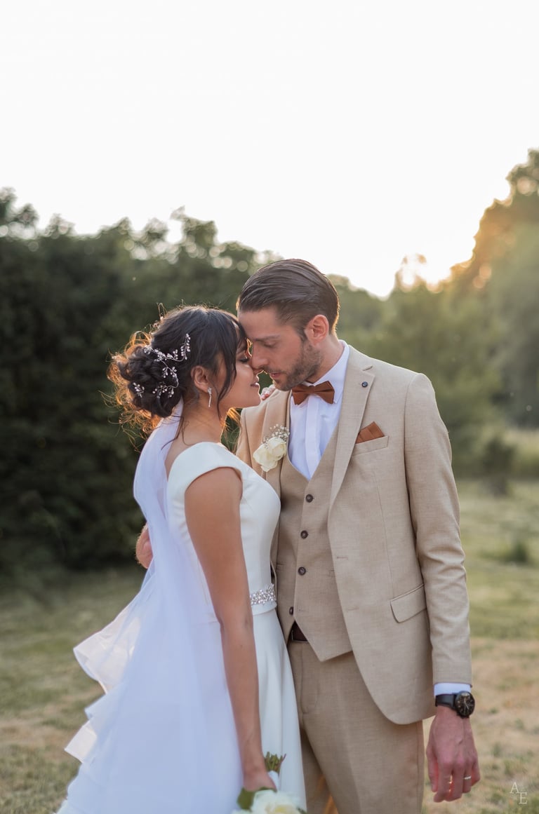un couple de mariés s'enlaçant debout au coucher du soleil