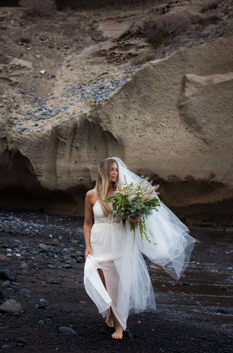Bride standing on a serene Tenerife beach during a romantic wedding photoshoot.