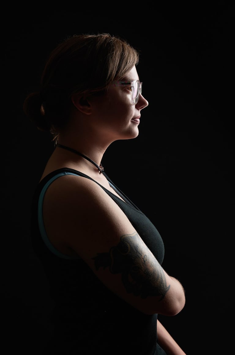 a woman with tattoos on her arm showing her profile with dramatic lighting