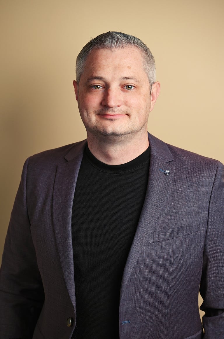 a man in a suit and black shirt with indoor lighting