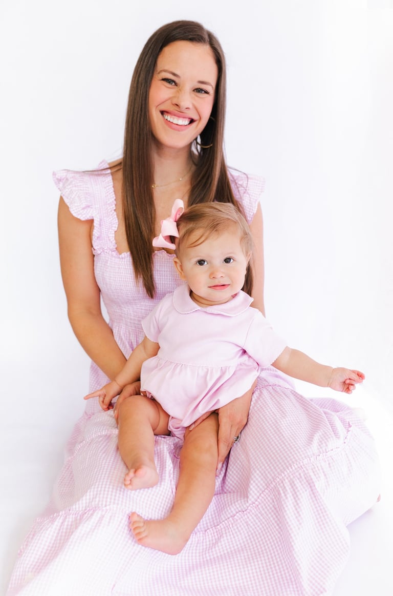 a mom in a pink dress sitting with her baby on her lap in a pink bubble