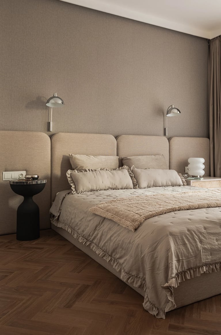 Fotograf wnętrz: beżowa sypialnia, panele tapicerowane na całą ścianę i parkiet jodełka.