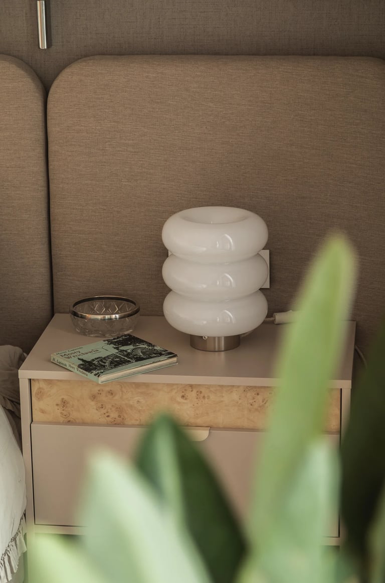 Detale w fotografii wnętrz: szafka nocna z frontem z czeczoty i lampka nocna vintage bubble.