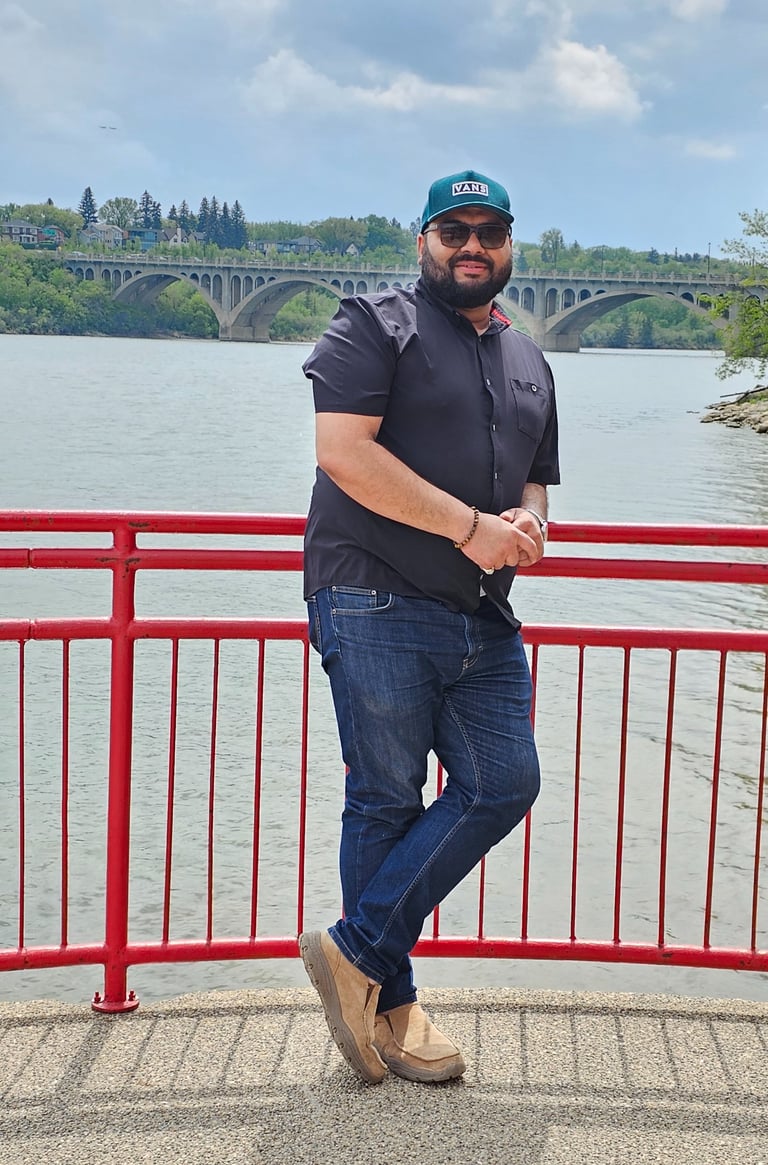 a man in a blue shirt and jeans standing on a bridge