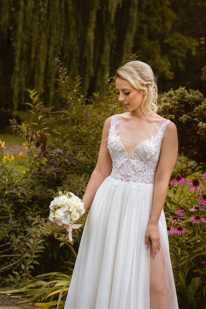 a woman in a white dress standing in front of a flower garden