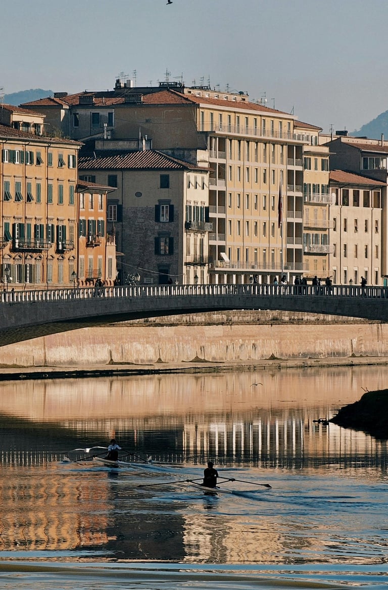 Rowers on the Arno River with colourful buildings and bridge in Pisa, Italy.