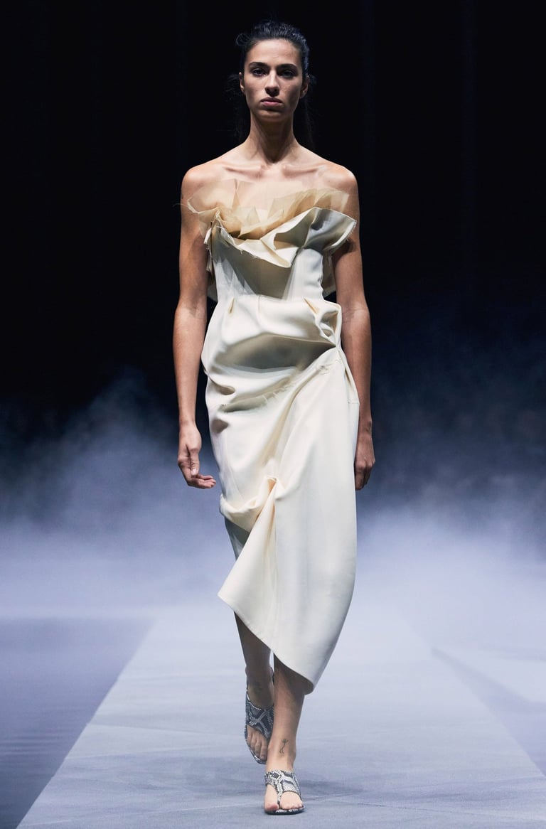 Khaite Spring/Summer 2026 runway model in an ivory off-shoulder draped dress.