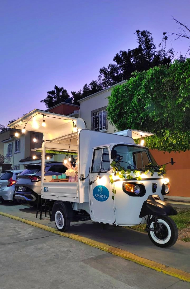 Piaggio italiano convertido en food truck con servicio de barra móvil de bebidas, en evento de noche