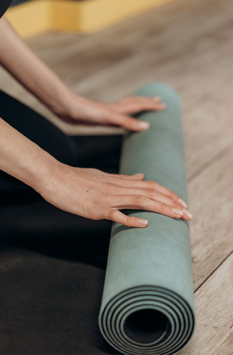 Hände, die eine Yogamatte aufrollen