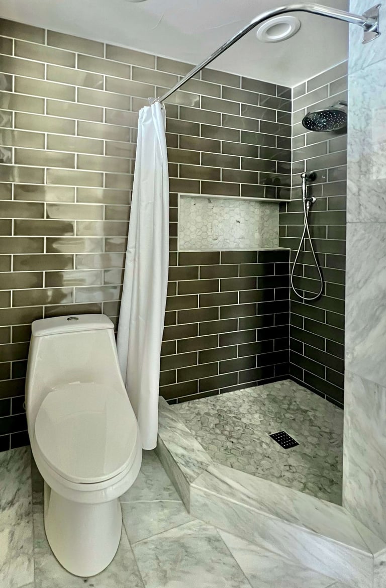 A bathroom with marble floor tile, and full height grey subway wall tile.