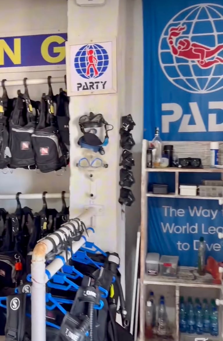 Scuba diving rental shop featuring PADI signs, snorkeling masks, and BCD jackets on racks.