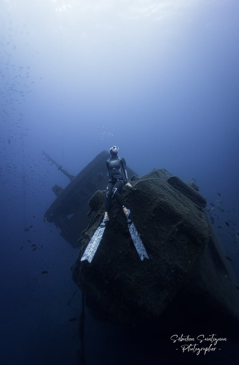 a freediver posing on top of a wreck ship. Photo taken by Sébastien Saintignan