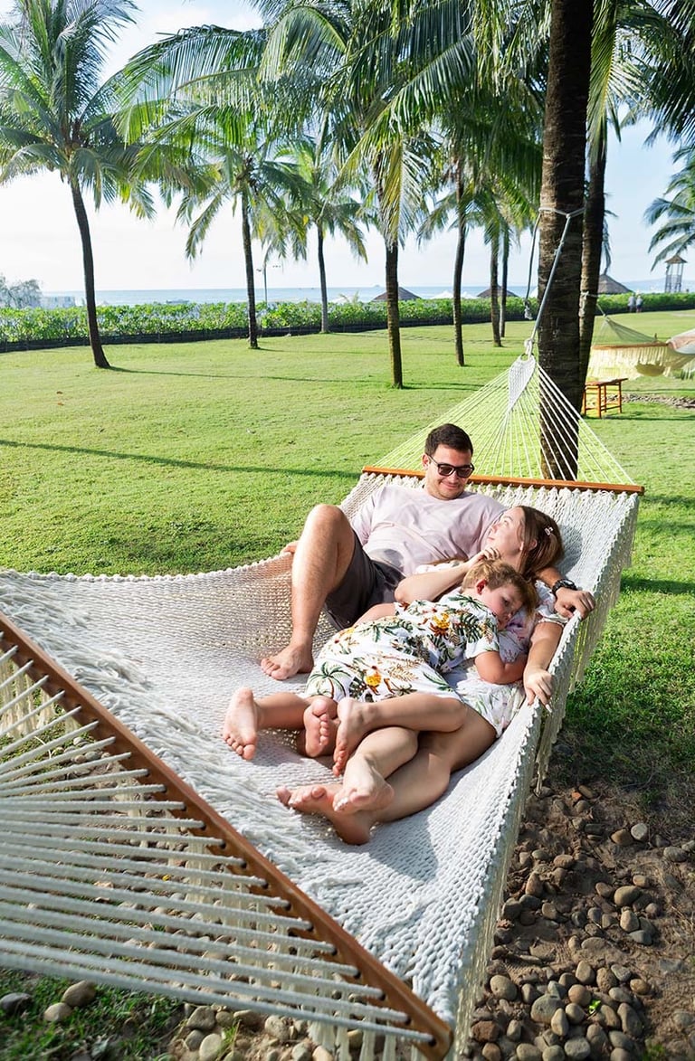Семья отдыхает в гамаке под пальмами в Radisson Blu Resort Phu Quoc