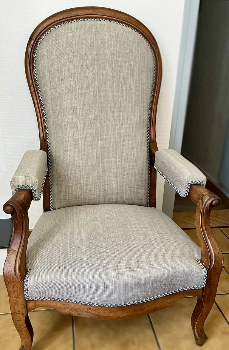 Chaise Voltaire avec assise en tissu gris et cadre en bois, dotée d'un dossier à bascule