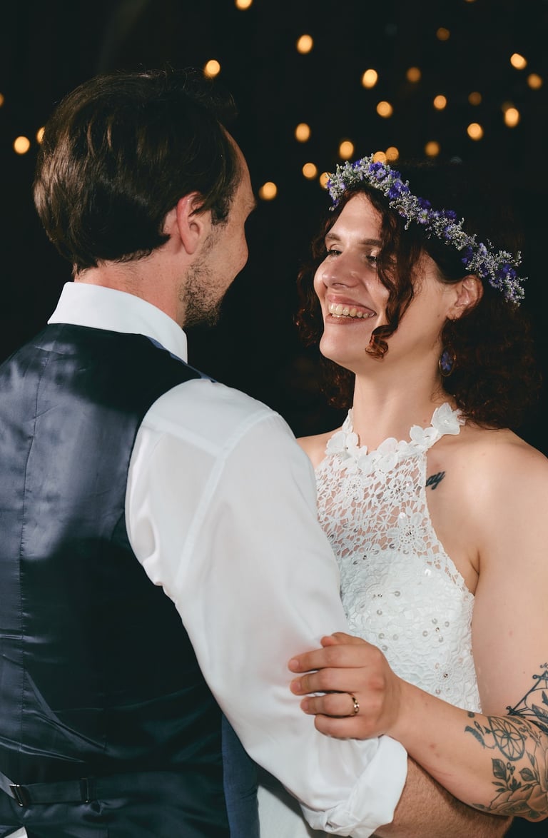 a bride and groom are dancing and smiling in front of lights