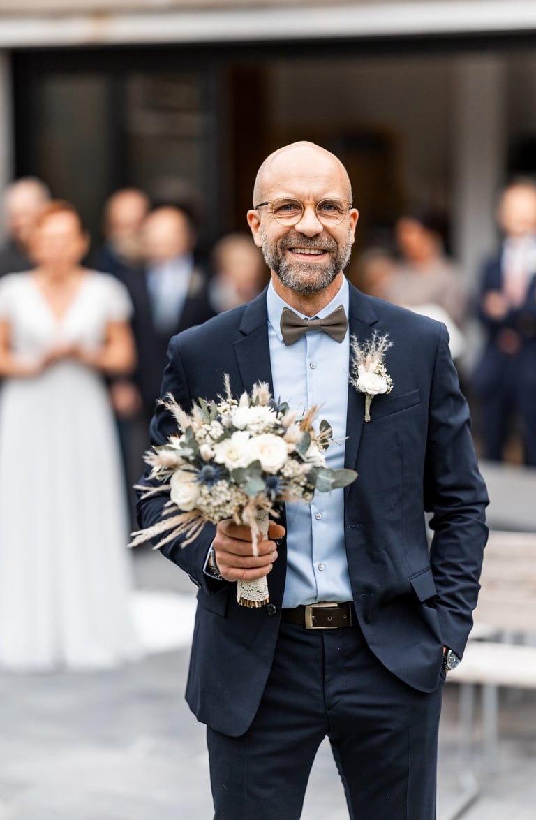 Un homme en costume avec un bouquet de fleurs à la main