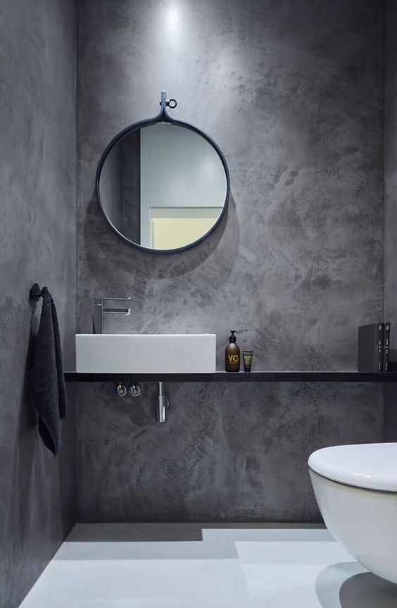 Badkamer afgewerkt met Mortex pleister, met een ronde wastafel en spiegel.