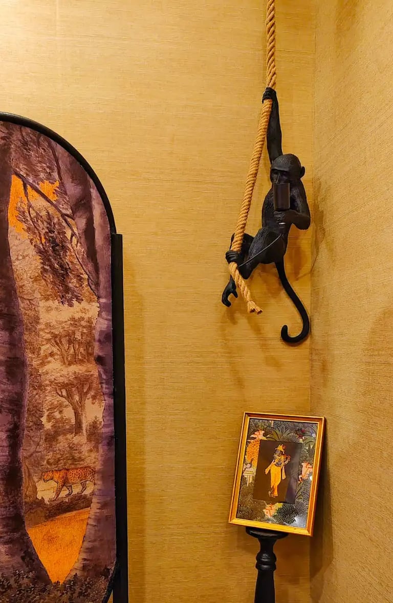 Black monkey hanging lamp with rope in a room featuring jungle themed wall art and decor.