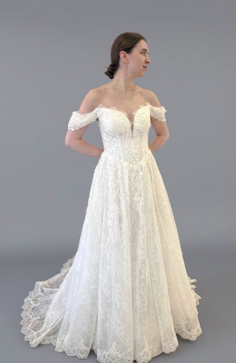 a woman in a white wedding dress with a lace overlayed off the shoulder