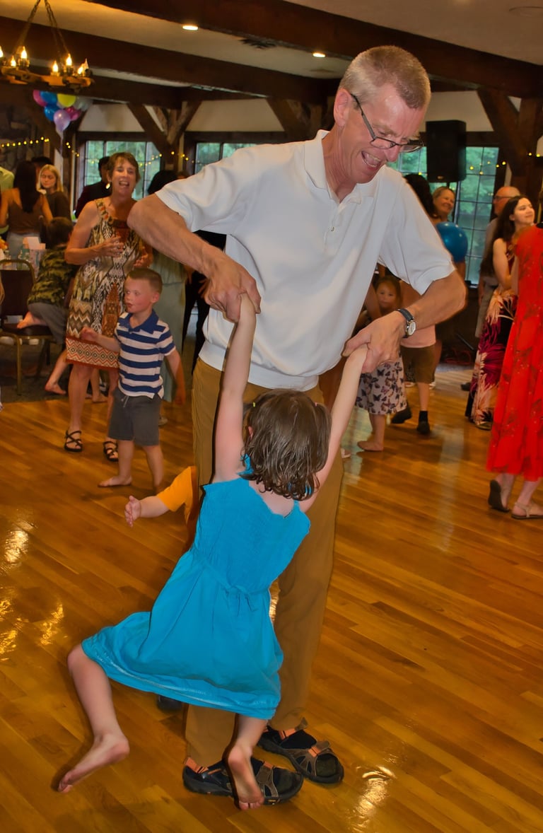 a grandfather and his granddaughter dancing at a party