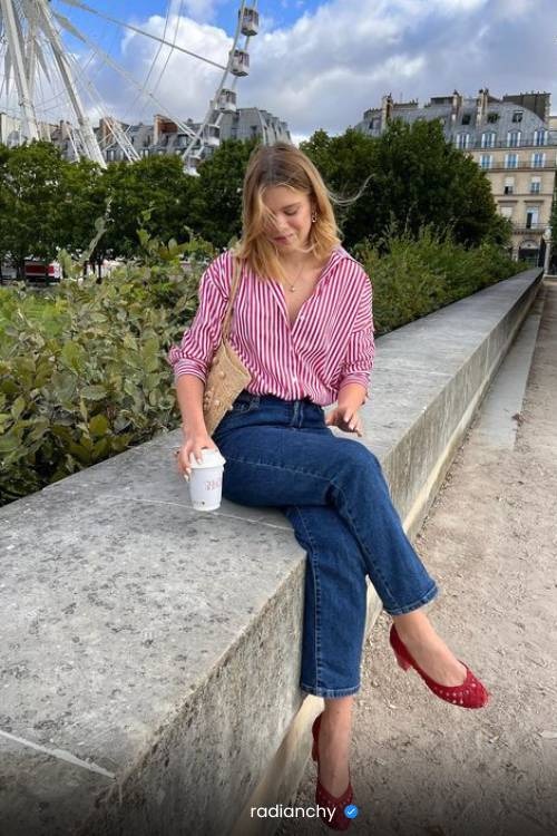 a woman sitting on a ledge with a cup of coffee