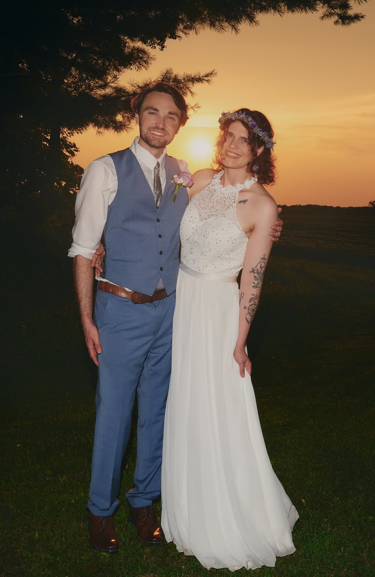 a bride and a groom standing in front of a sunset