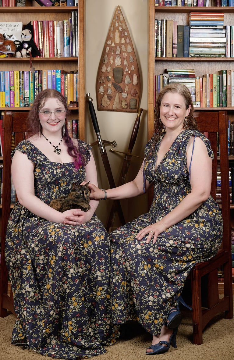a mother and a daughter in matching dresses with a cat are posing for a photo