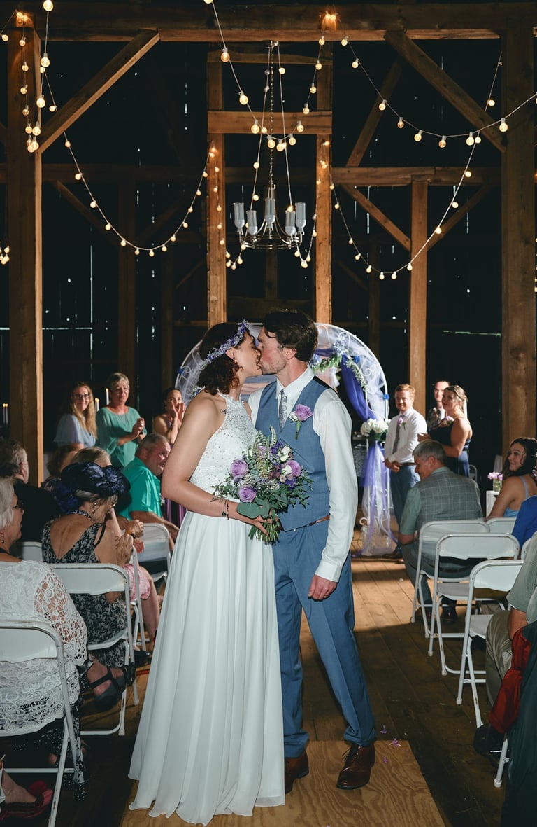 a bride and groom kissing in a barn wedding