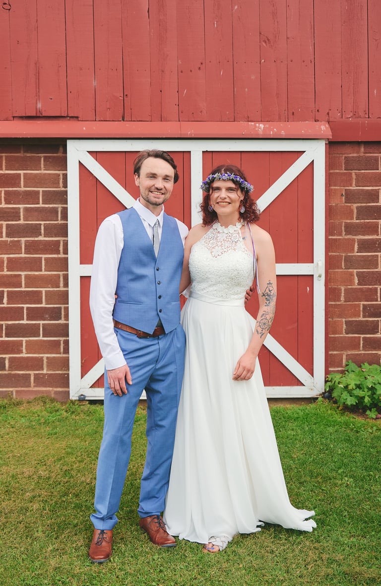 a bride and a groom standing in front of a barn