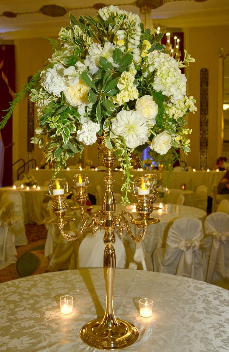 a tall gold fancy candle holder with candles and flower