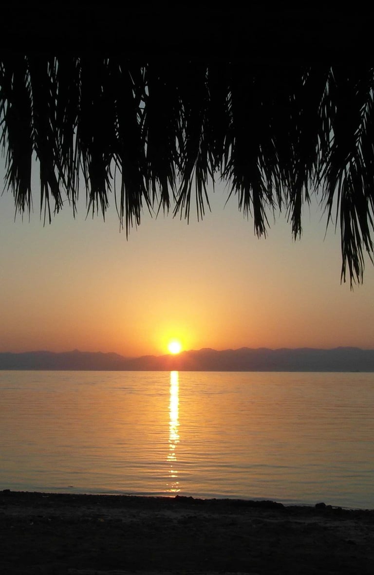 a sunrise over the red sea with a view of the sun rising 