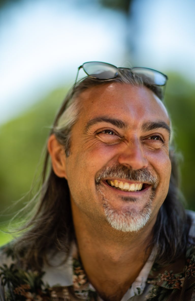 a man smiling with long hair and sunglasses on his head