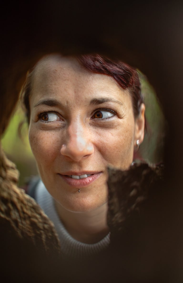 a woman smiling though a tree hole in the woods