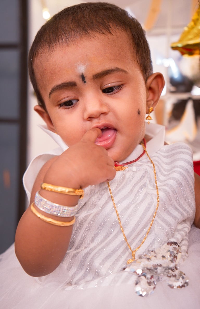 a young child with a white dress and gold jewelry