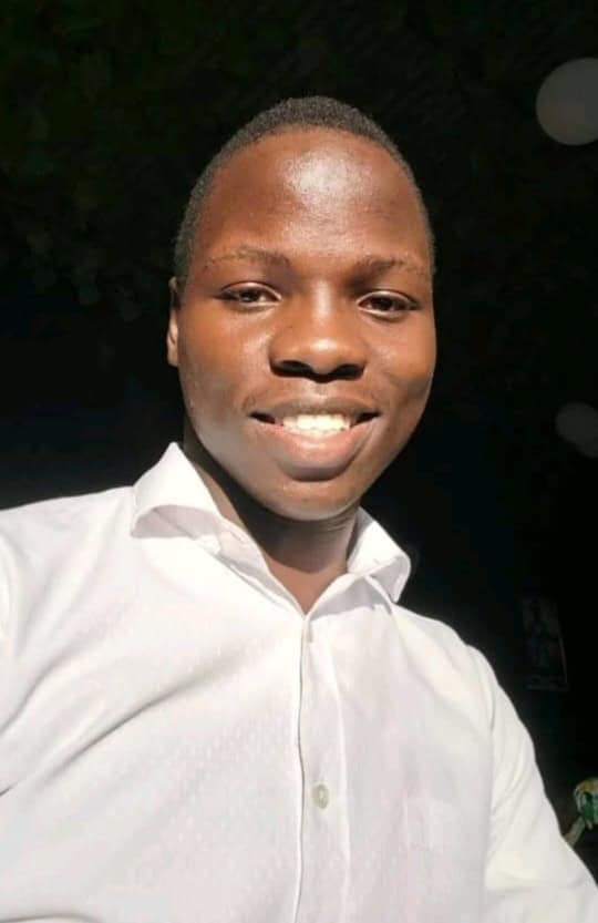 Smiling young African man wearing a professional white button-down shirt in natural sunlight.