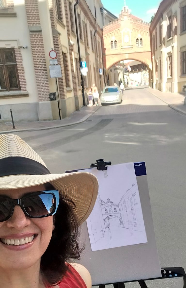 Mag Wilk ( Magdalena Wilk-Dyszkiewicz) in a hat and sunglasses is holding a drawing of a house