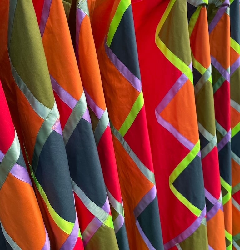 Vibrant geometric patchwork fabric with colorful diamond patterns and ribbon trim detailing.
