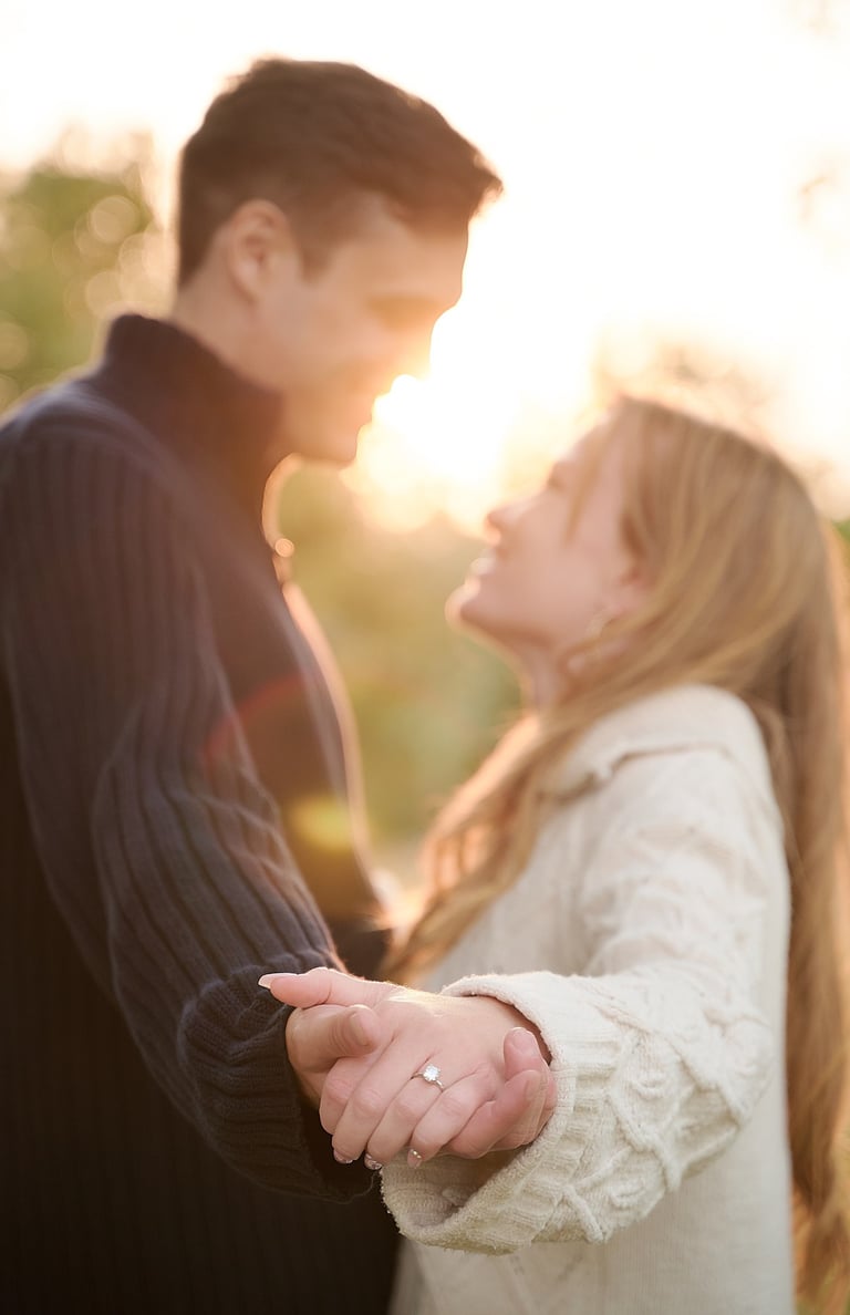 a man and woman holding hands and looking at each other showing the engagement ring in the front