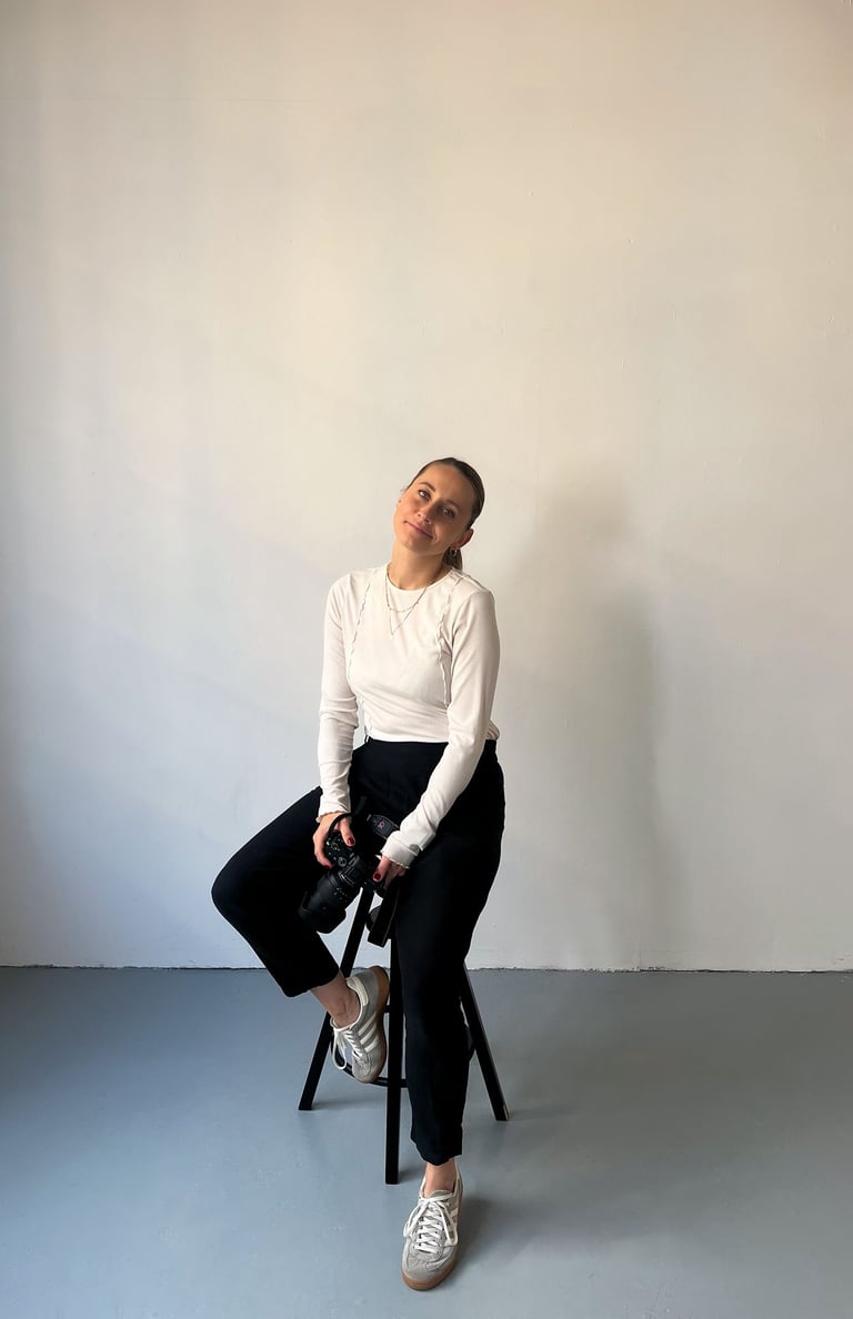 woman sitting on the bar chair holding a camera and smiling 