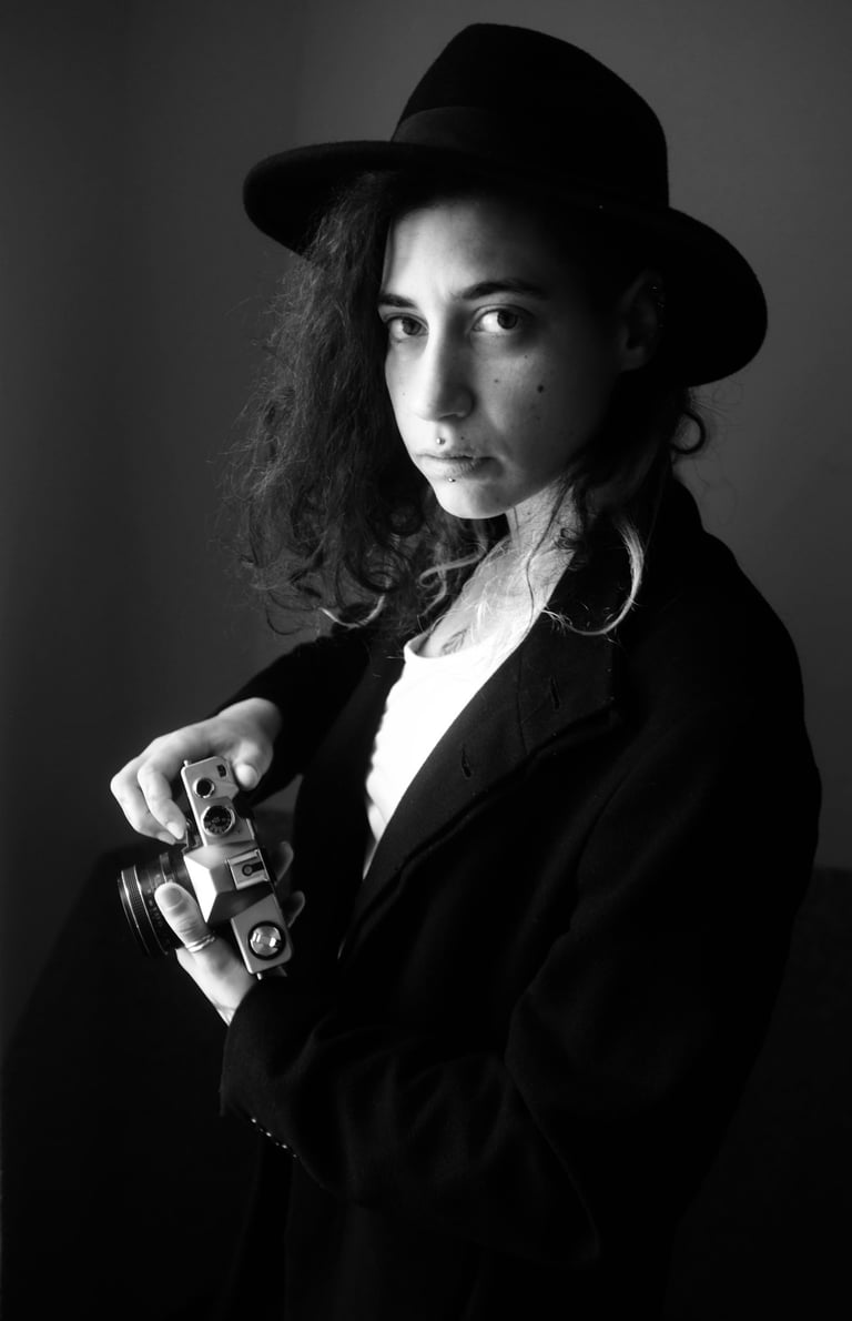 a woman photographe with a hat posing for a photo