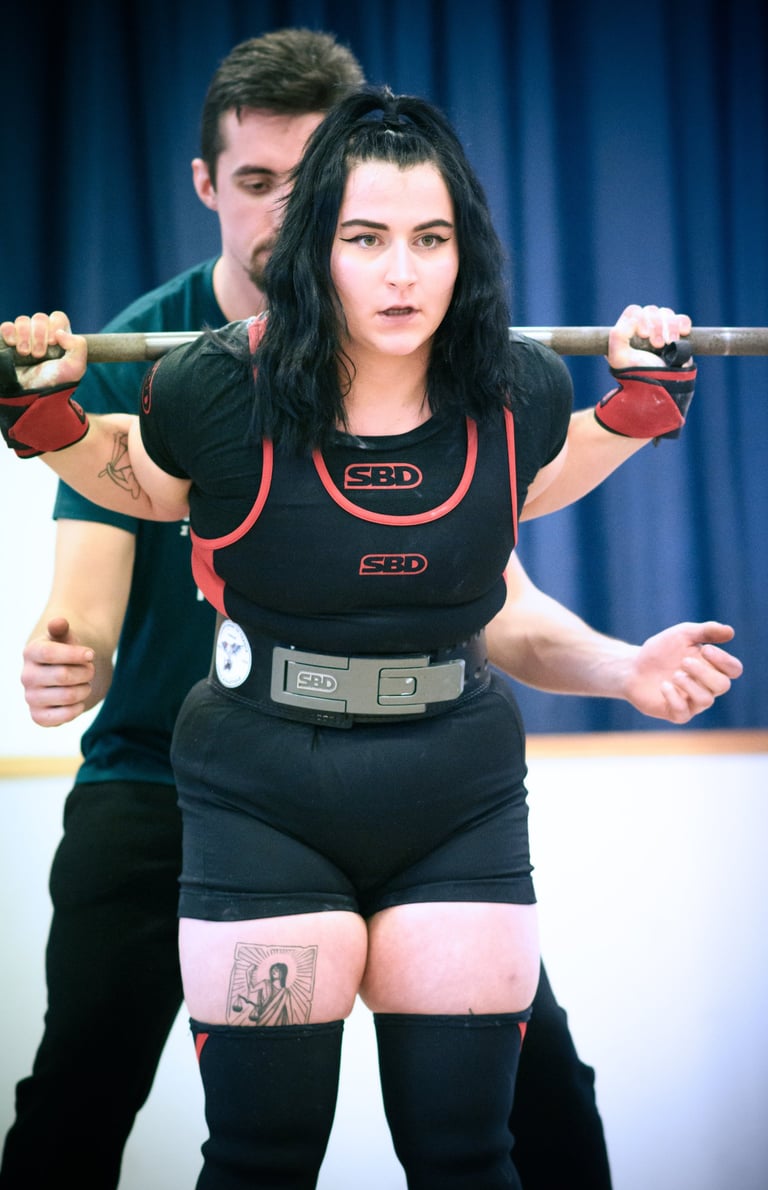 Une jeune femme en singlet pratiquant le squat pour une compétition de powerlifting