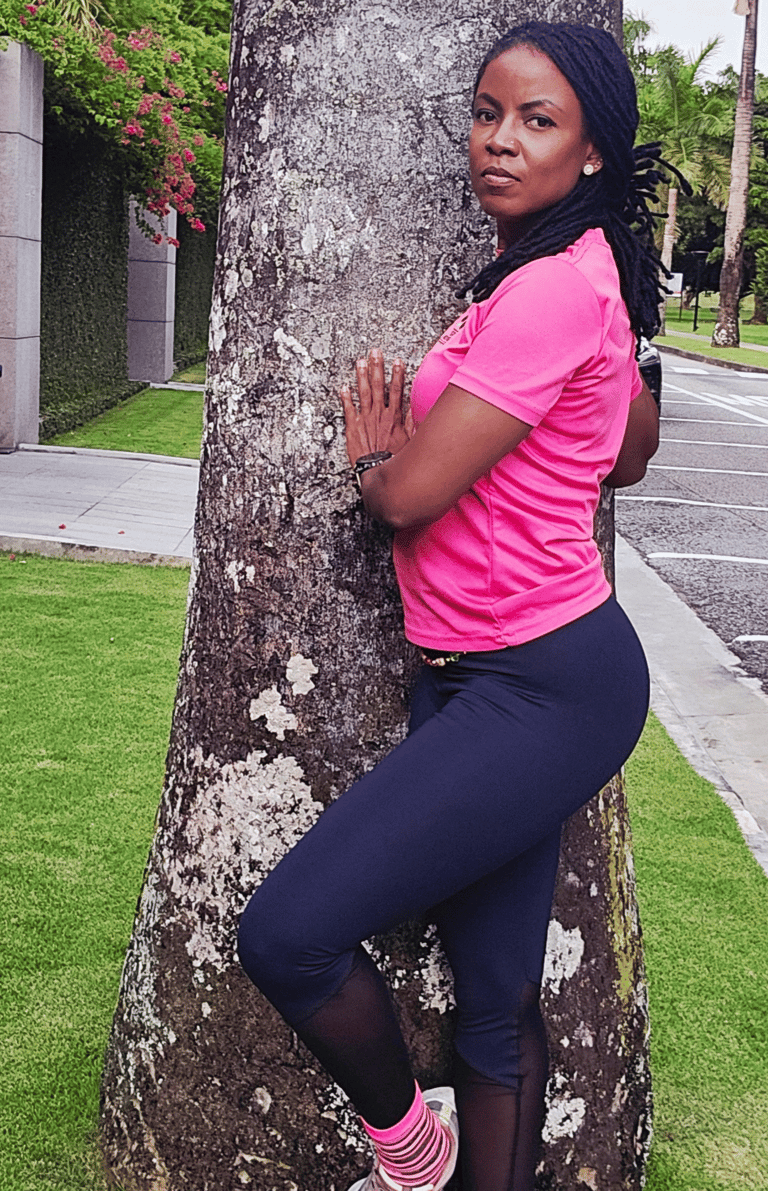 a woman in a pink shirt is leaning against a tree