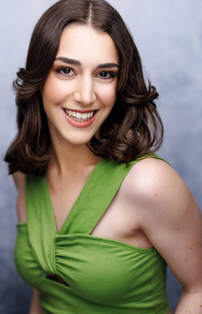 Smiling woman with shoulder-length brown hair wearing a bright green sleeveless top. 