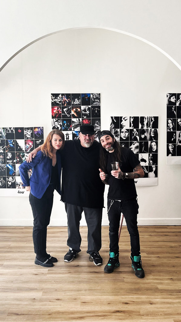 Artists posing in a modern art gallery with black and white photography portraits on the wall.