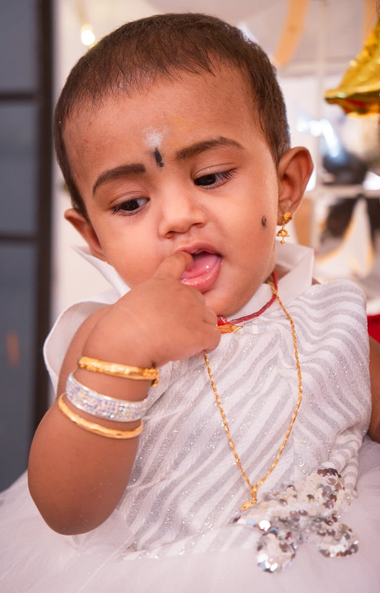 a young child with a white dress and gold jewelry