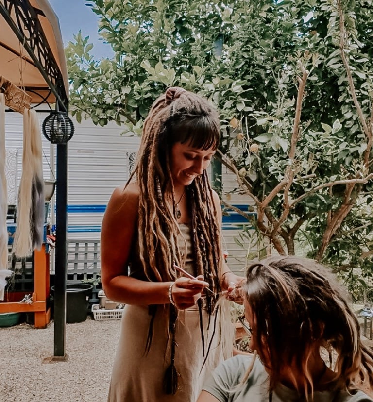 a woman dreadlocking a woman's hair