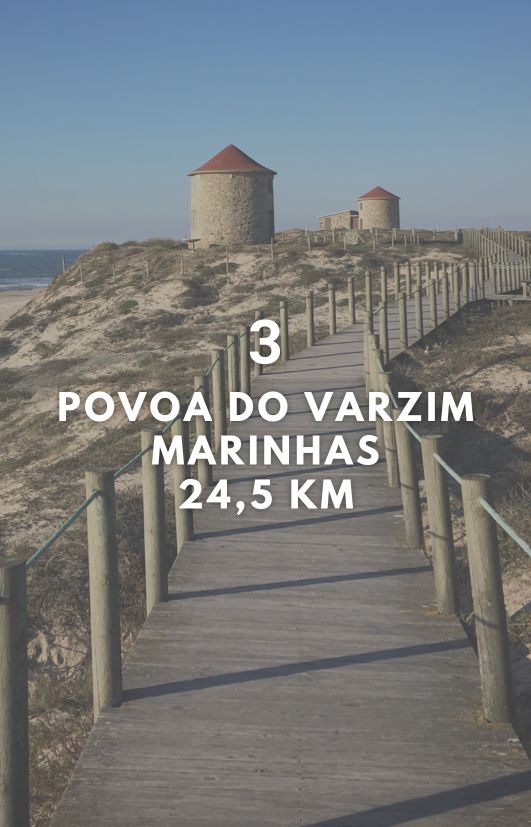 a wooden walkway leading to a beach with a lighthouse in the background